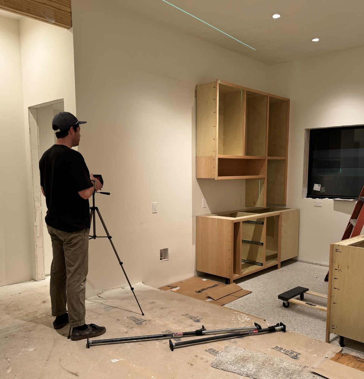 Mike checking a fresh cabinet install with a laser level on an Austin job site